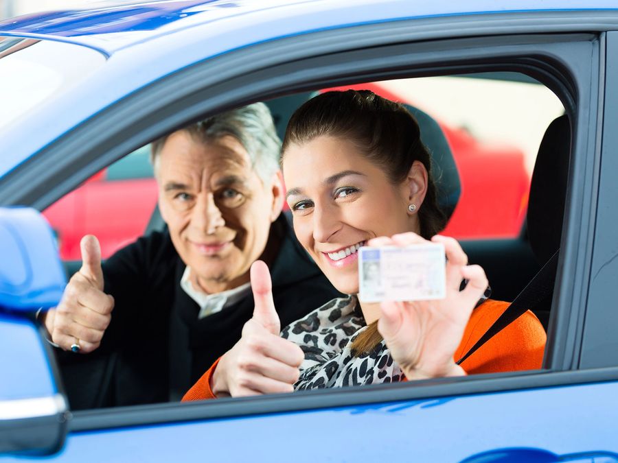 Adult student holding up her new license with her instructor