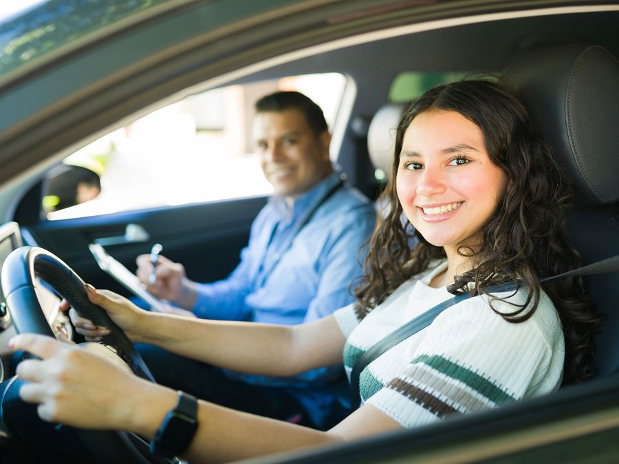 Smiling teen driver at the wheel with her instructor